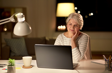 Image showing senior woman with laptop at home in evening