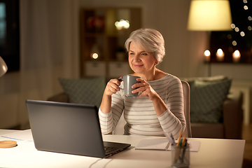 Image showing senior woman with laptop drinking coffee at home