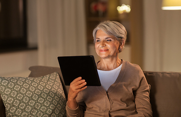 Image showing happy senior woman with tablet pc at home at night