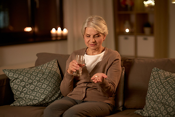 Image showing senior woman with water and medicine at home