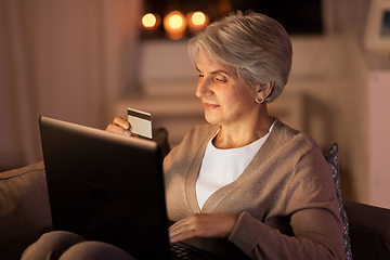 Image showing senior woman with laptop and credit card at night