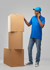 Image showing indian delivery man with boxes calls on smartphone