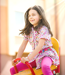 Image showing Young happy girl is swinging in playground