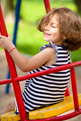 Image showing Young happy girl is swinging in playground