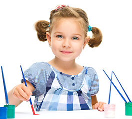 Image showing Little girl is painting with gouache