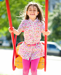 Image showing Young happy girl is swinging in playground
