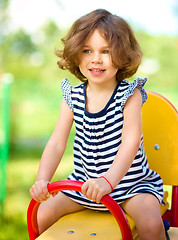 Image showing Young happy girl is swinging in playground