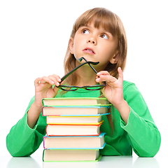 Image showing Young girl is daydreaming while reading book