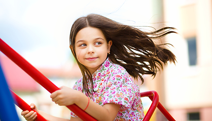 Image showing Young happy girl is swinging in playground