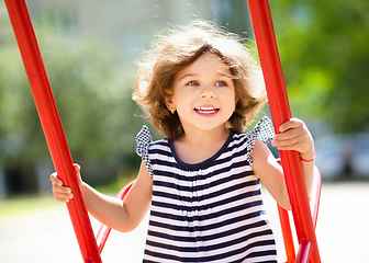 Image showing Young happy girl is swinging in playground