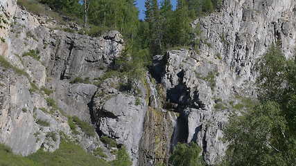 Image showing Big beautiful waterfall flows down the rocks mountains