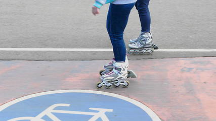 Image showing Feet of two girls riding on a roller skates ride on asphalt.