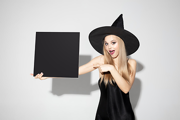 Image showing Young woman in hat as a witch on white background