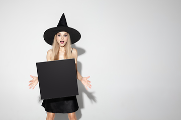 Image showing Young woman in hat as a witch on white background