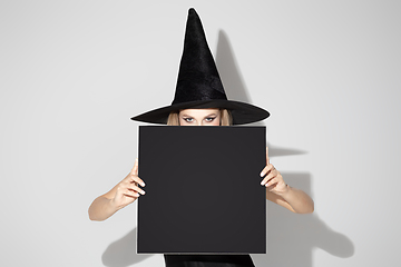 Image showing Young woman in hat as a witch on white background