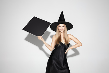 Image showing Young woman in hat as a witch on white background