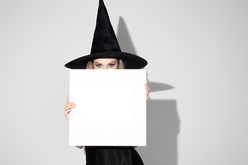 Image showing Young woman in hat as a witch on white background