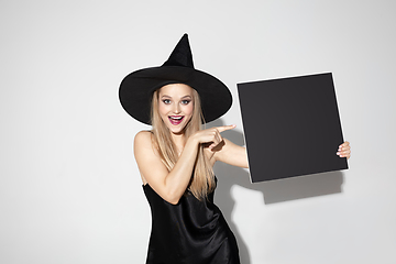 Image showing Young woman in hat as a witch on white background