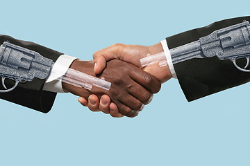 Image showing Two male hands shaking isolated on blue studio background