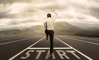 Image showing Businessman jumping on a starting grid with cityscape on the background