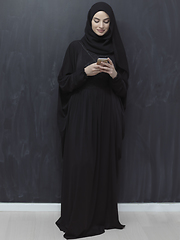 Image showing Young muslim businesswoman in traditional clothes or abaya using smartphone