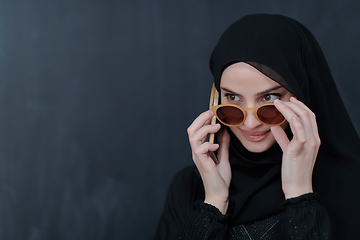 Image showing Young muslim businesswoman in traditional clothes or abaya using smartphone