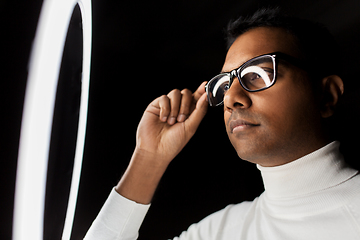 Image showing man in glasses under white illumination over black