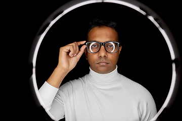 Image showing man in glasses over white illumination on black