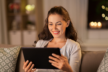 Image showing happy woman with tablet pc at home in evening