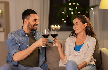 Image showing happy couple drinking red wine at home in evening