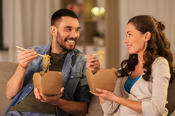 Image showing happy couple eating takeaway noodles at home