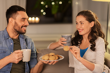 Image showing happy couple drinking tea with cookies at home