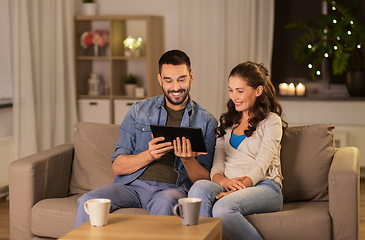 Image showing happy couple using tablet pc at home in evening