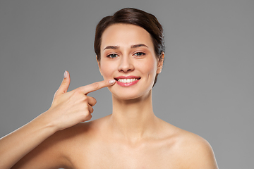Image showing smiling young woman pointing to her mouth