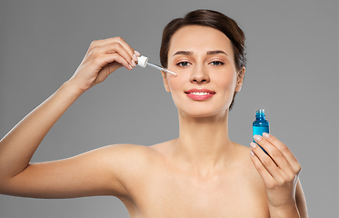 Image showing woman with dropper applying serum to her face