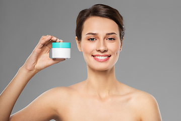 Image showing happy young woman holding jar of cream