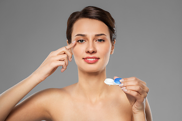 Image showing happy young woman applying contact lenses