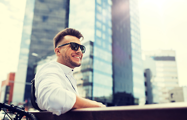 Image showing happy young man with bicycle sitting on city bench