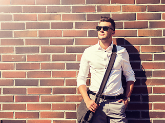 Image showing young man in sunglasses with bag over brickwall