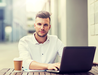 Image showing man with laptop and coffee at city cafe