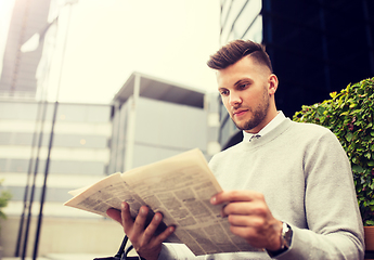 Image showing man reading newspaper on city street bench