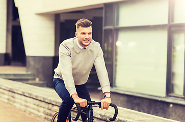 Image showing young man riding bicycle on city street