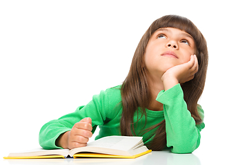 Image showing Young girl is daydreaming while reading book