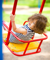 Image showing Young happy girl is swinging in playground