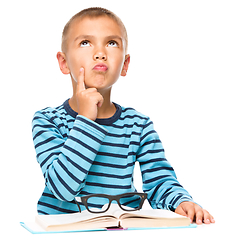 Image showing Young boy is daydreaming while reading book