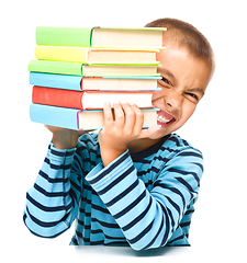 Image showing Little boy is holding a pile of books