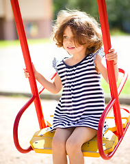 Image showing Young happy girl is swinging in playground