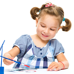 Image showing Little girl is painting with gouache