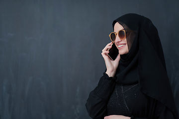 Image showing Young muslim businesswoman in traditional clothes or abaya using smartphone