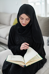 Image showing Portrait of young muslim woman reading Quran in modern home